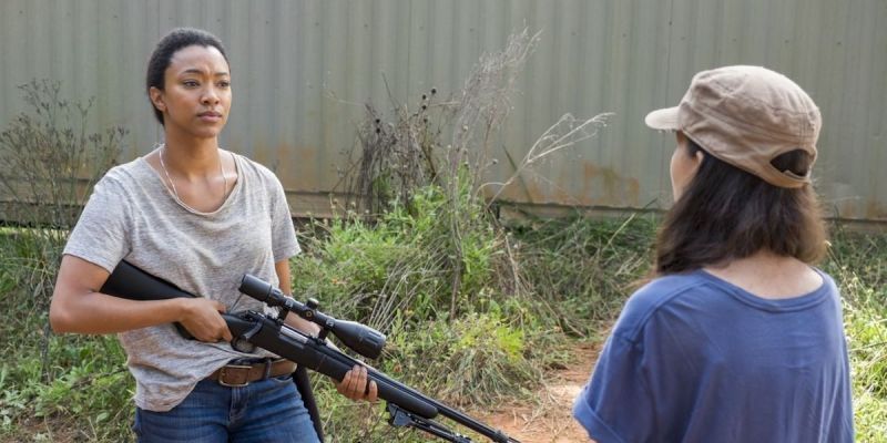 Sasha, sosteniendo su rifle de francotirador, habla con Rosita en
