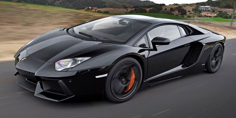 Lamborghini Aventador negro acelerando por una carretera rural